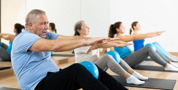 istock People of different ages pressing core and clutching mini Pilates balls between legs during Pilates training together 1466492988