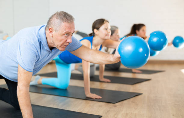 istock Aged man exercising with pilates ball during group training 1466492997