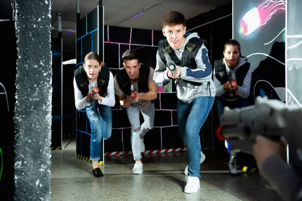 Photo of Portrait of teenager boy with laser gun having fun on dark lasertag arena