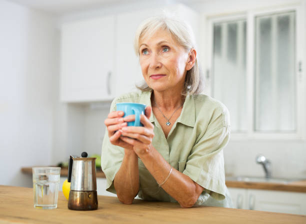 istock Positive old woman drinking coffee in kitchen at home 1466497058
