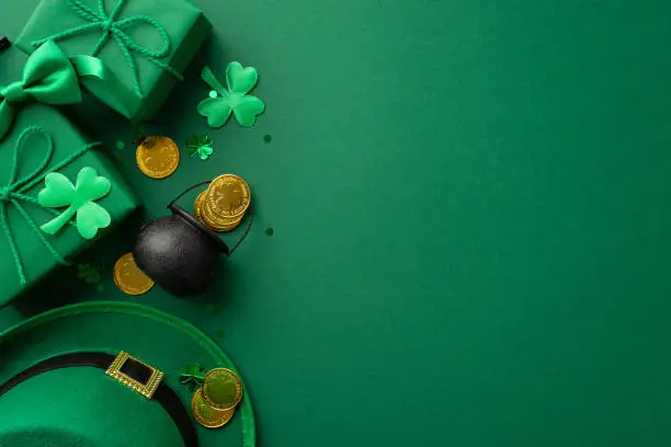 Photo of St Patrick's Day concept. Top view photo of leprechaun headwear gift boxes pot with gold coins bow-tie clovers and confetti on isolated green background with empty space