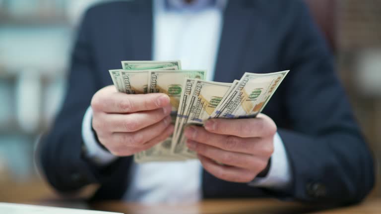 Close up hands of business man investor counting dollars banknotes at desk in modern office Successful entrepreneur holding money