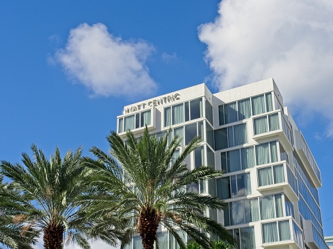 Miami Beach, FL - USA, February 1, 2023. The Hyatt Centric along Collins Avenue in Miami Beach Florida. Palm trees, blue sky background with puffy clouds and copy space.