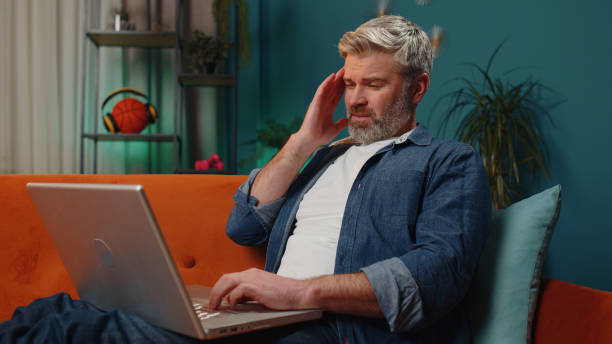 istock Tired mature man freelancer use laptop suffering from headache problem tension and migraine, stress 1466510797