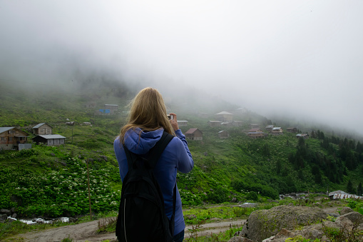 A young girl photographing with a mobile cell phone on a high plateau. Photo was taken in plateau in Rize, Karadeniz region of Turkey.