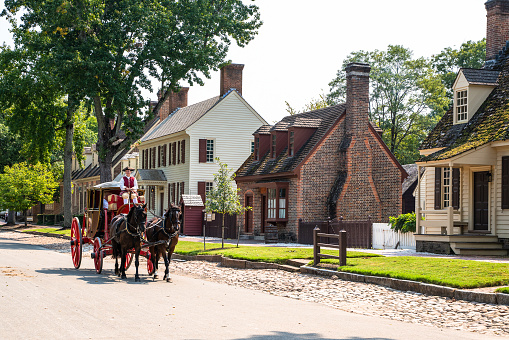 Williamsburg, Virginia, USA - September 12, 2021:  Street scene with horse drawn carriage along the street in historic Colonial Williamsburg VA.