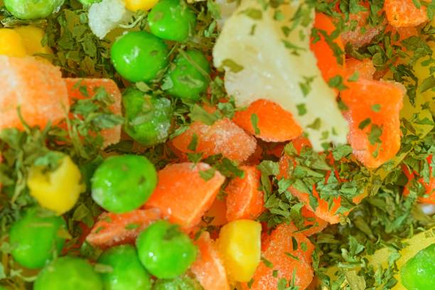 Close-up view of the soup vegetables with carrots, peas, cauliflower, corn and parsley. Texture of frozen soup vetetables. Frozen soup vegetables. Frozen soup vegetables ready to cook Flat design, top view. Macro background. Horizontal image. Partly defocused. vista de cerca de la sopa de verduras con zanahorias, guisantes, coliflor, maíz y perejil. textura de sopas congeladas vetetables. sopa de verduras congeladas. sopa de verduras congeladas listas para cocinar diseño plano, vista superior. fondo macro. ima