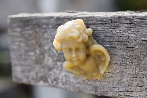 cherub sculpture at a wooden grave cross on a cemetery