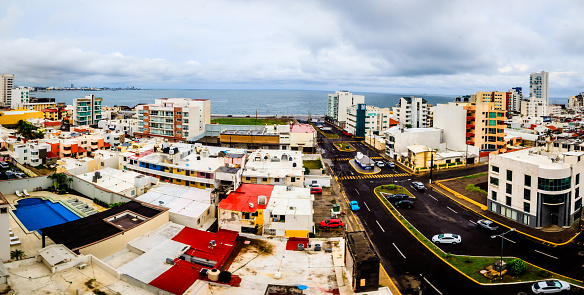 Ciudad en un día nublado con mar en el fondo, edificios blancos, autos en las calles, puerto de boca del río Veracruz