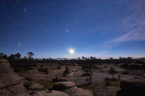 Paisaje nocturno, rocas enormes y cielo oscuro con estrellas, planeta venus en el cielo, arboles en paisaje volcanico, pleiades, sierra madre occidental en mexiquillo durango