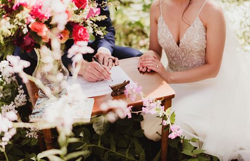 Close up of bride and groom signing the marriage license