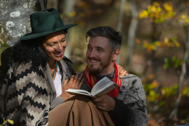 istock A couple in love is sitting in the forest with a book. 1466527680