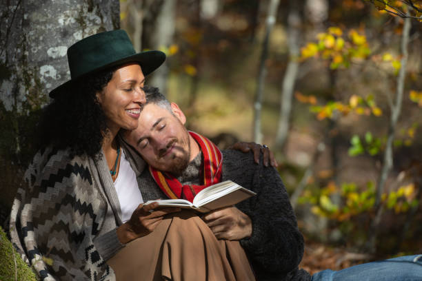 istock A couple in love is sitting in the forest with a book. 1466527695