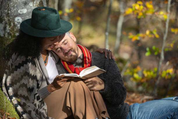 istock A couple in love is sitting in the forest with a book. 1466527700
