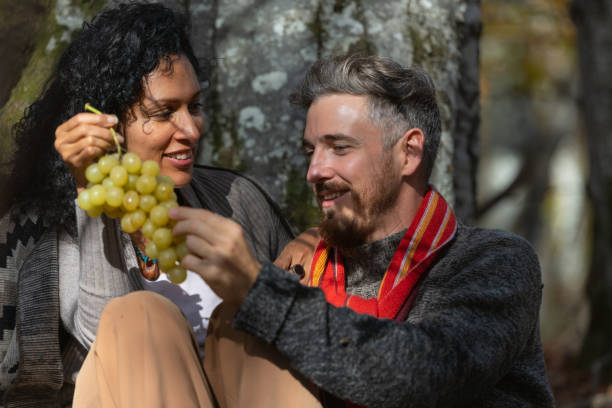 A couple eats grapes on a picnic in nature.