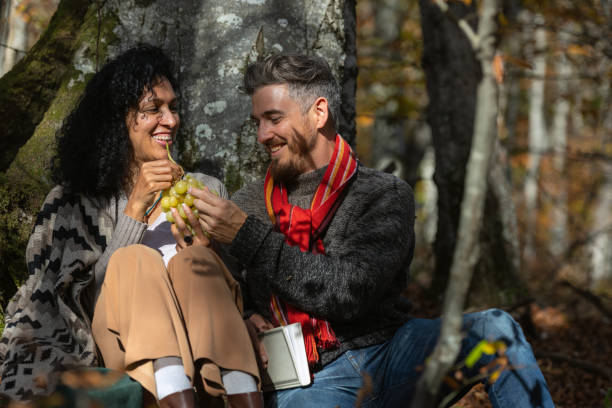 A couple eats grapes on a picnic in nature.