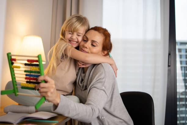 anya segíti lányát a házi feladat írásában otthon - gyermekelhelyezés témájú stock jellegű vizuális alkotások, jogdíjmentes fotók és képek