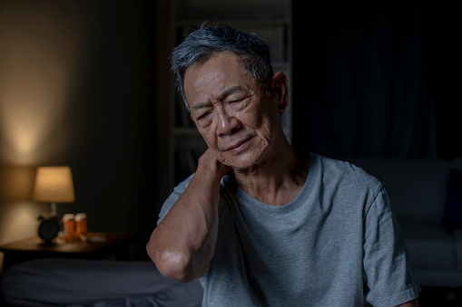 Insomnia senior Asian man suffering from neck and shoulder pain at night.