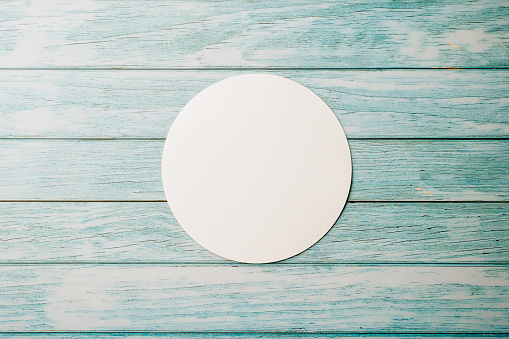 Top view blank round white paper isolated on blue wooden background, abstract geometric shapes, with copy space design element background, paper circle