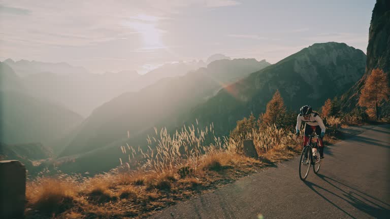 Cyclist riding bicycle uphill in sunny scenic mountains