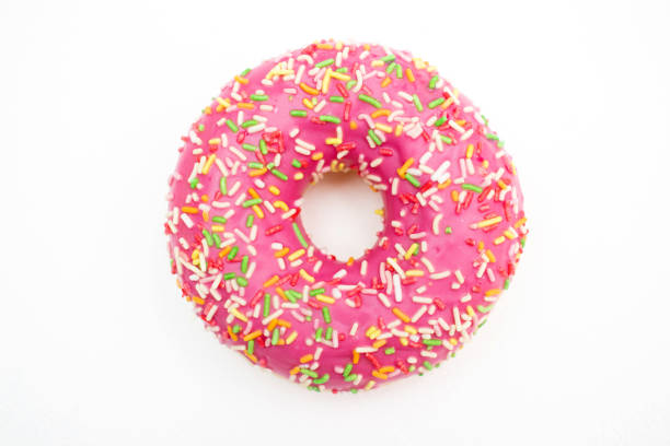istock Pink donut decorated with colorful sprinkles isolated on white background. 1466554891