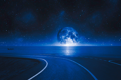 asphalt road and seascape at full moon at night sky