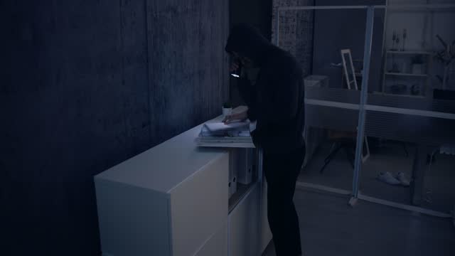 Robber With Flashlight Searching For Documents In Office