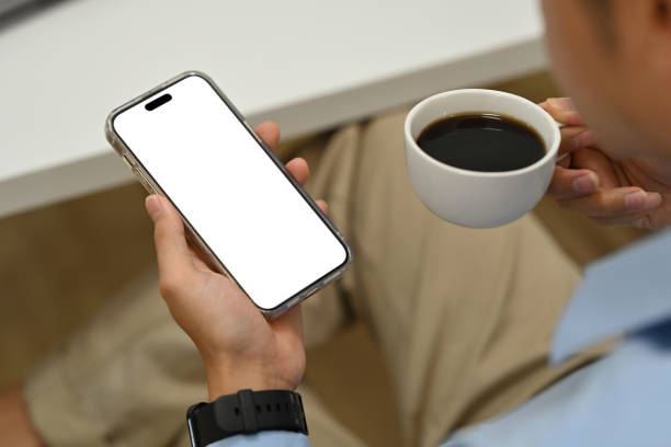 istock Cropped image of man drinking coffee and using smart phone. Blank screen for advertise text and graphic display montage. 1466587326