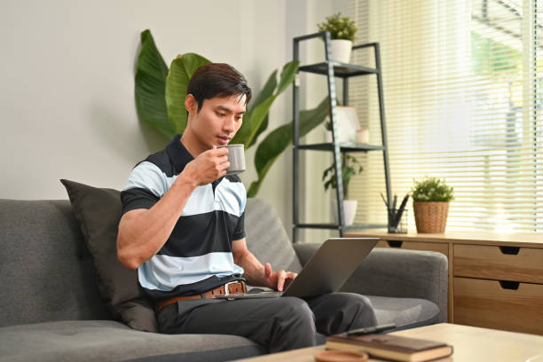 istock Handsome asian man looking at screen, watching video or surfing internet in comfortable home. 1466587368