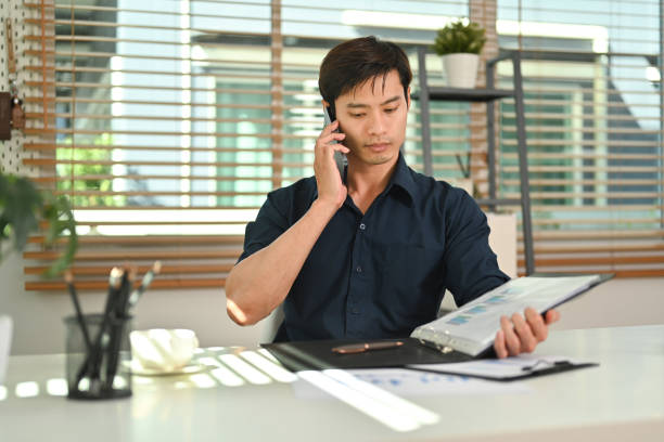 istock Attractive asian man having phone conversation while working remotely from home. 1466587411
