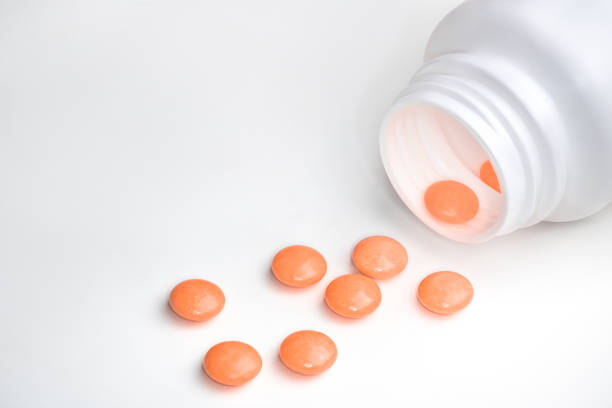 istock Spilled orange pills from open prescription medication plastic white bottle 1466587631