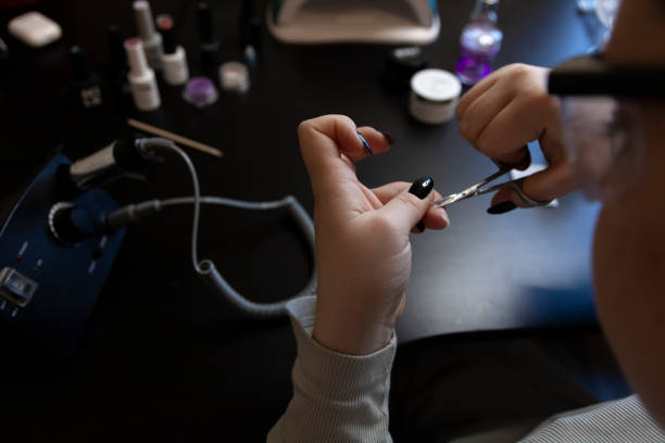 istock Girl cuts off cuticle with manicure scissors near manicure tools on background 1466587853