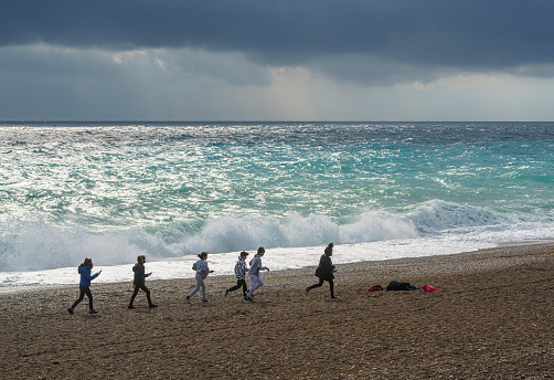 Antalya, Turkiye - 27 December, 2021: Large group of children are playing on the beach after the storm, Antalya, Turkiye