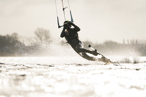 Kitesurfer performing a darkslide trick in backlit conditions
