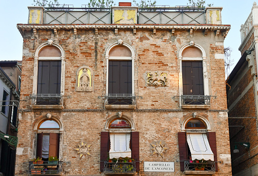 Venice, Veneto, Italy - 08 23 2022: Seven golden reliefs adorn the façade of this ancient palace in the sestiere of Cannaregio.