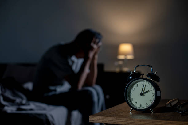 ベッドに座っているうつ病の年配のアジア人男性は不眠症から眠ることができません - 夜 ストックフォトと画像