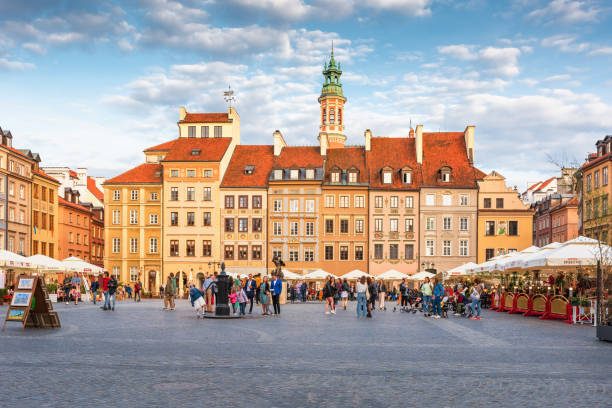 casas coloridas típicas na praça do mercado (plac kanonia, em polonês) na cidade velha de varsóvia, com o histórico sino dos desejos no meio. vista com céu bonito em um dia ensolarado brilhante - restore ancient ways - fotografias e filmes do acervo