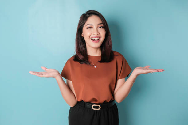 istock Smiling beautiful Asian woman pointing finger sideward to empty space isolated blue background 1466603071