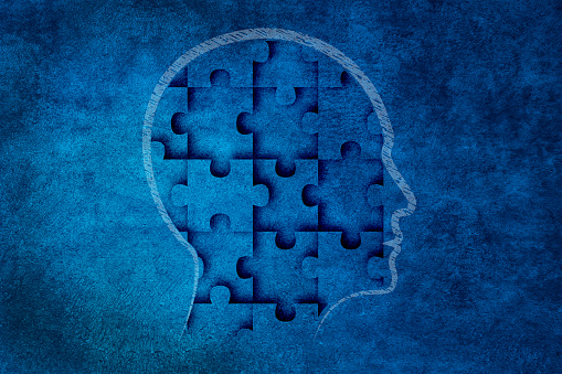 Head made of jigsaw puzzle on textured abstract blue wall background