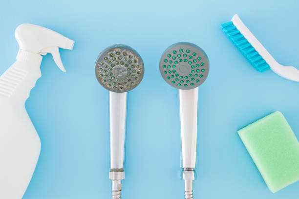 istock Detergent bottle, brush, sponge for shower head cleaning on pastel blue table background. Limescale removing. Closeup. Problem and solution. Compare two objects with and without limestone. Top view. 1466606944