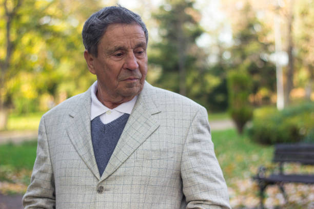 Older man with wrinkled and serious face, outdoor walking