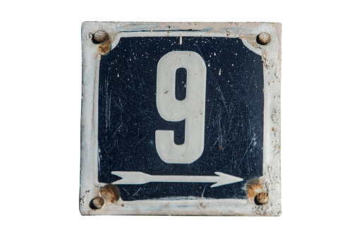 Weathered grunge square metal enameled plate of number of street address with number 9 closeup isolated on white background