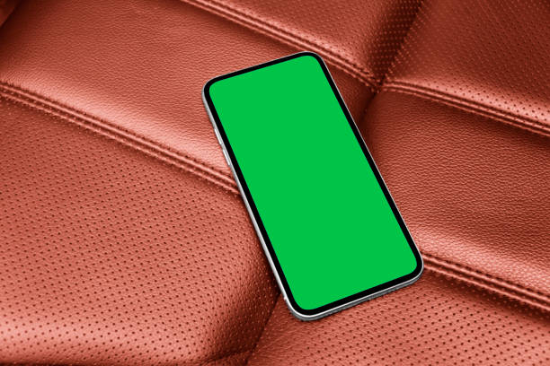 istock Smartphone in a car use for navigate or GPS. Driving a car with smartphone. Mobile phone with isolated green screen with chroma key on red perforated lether seat. Copy space. 1466609210