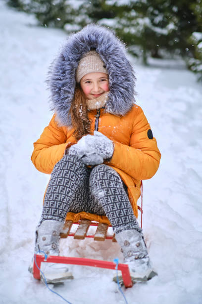 istock Child sledding, sits on a sled and throws snow. 1466610101