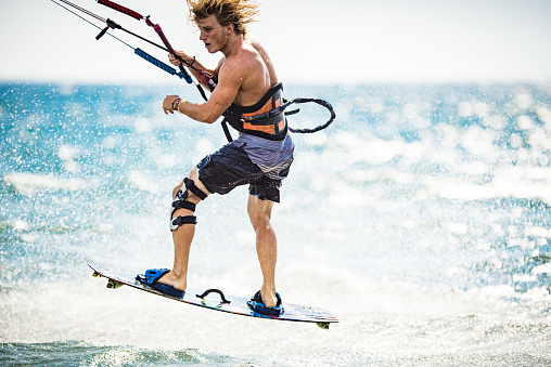 Young man enjoying in kiteboarding during summer day at sea. Copy space.