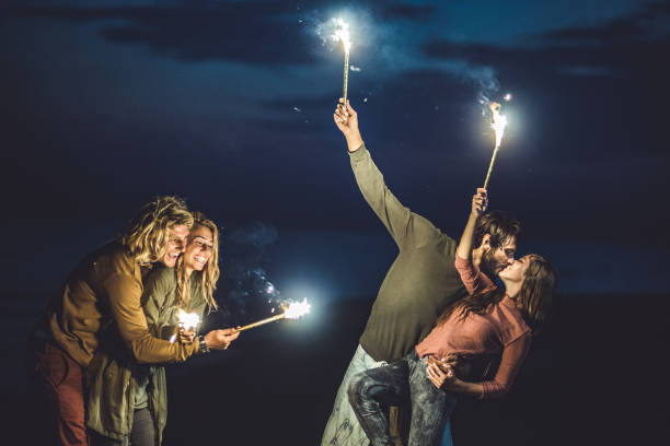 Cheerful friends having fun with flaming torches by night. Copy space.