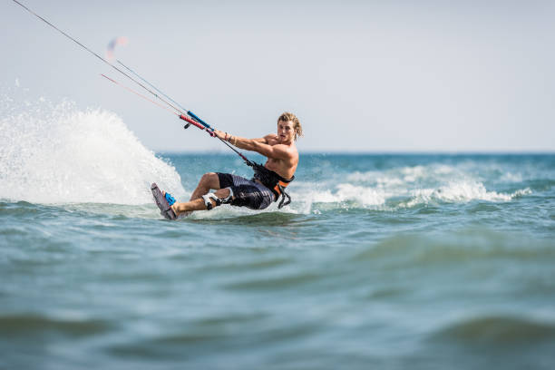 Young man enjoying in kiteboarding during summer day at sea. Athletic man having fun while kitesurfing on the sea. Copy space. kiteboard stock pictures, royalty-free photos & images