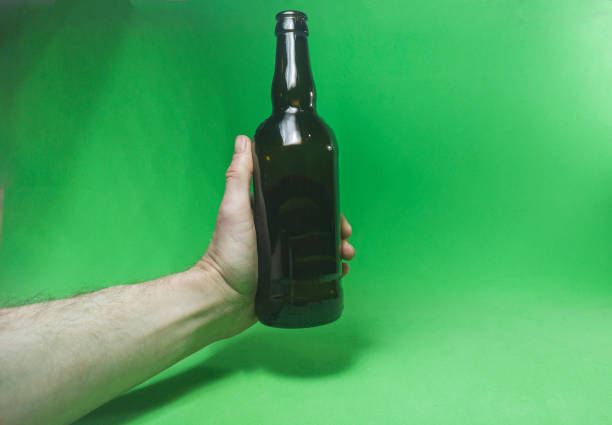 istock beer brown bottle in hand on green background 1466612174