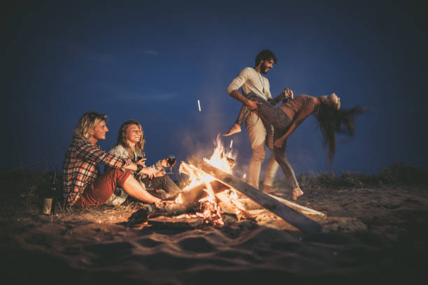 istock Happy couples having fun on a night party at the beach by the campfire. 1466612176