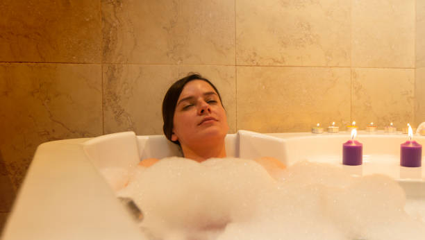 istock Young woman taking a bubble bath in the bathroom with burning candles 1466612746